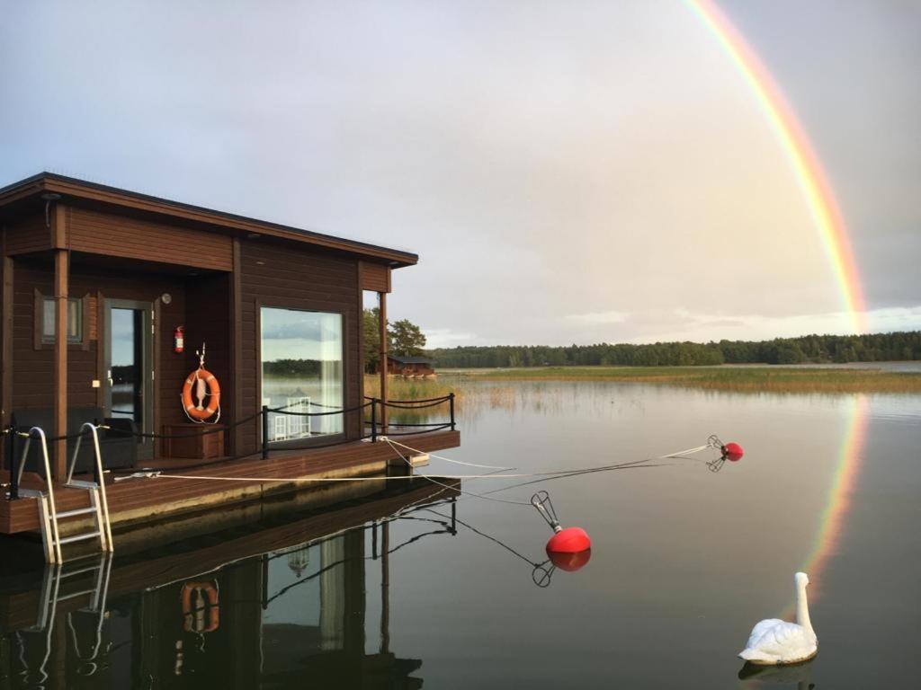 ein Haus auf einem Dock mit Regenbogen im Hintergrund in der Unterkunft Saunaboat Haikara in Jorvas