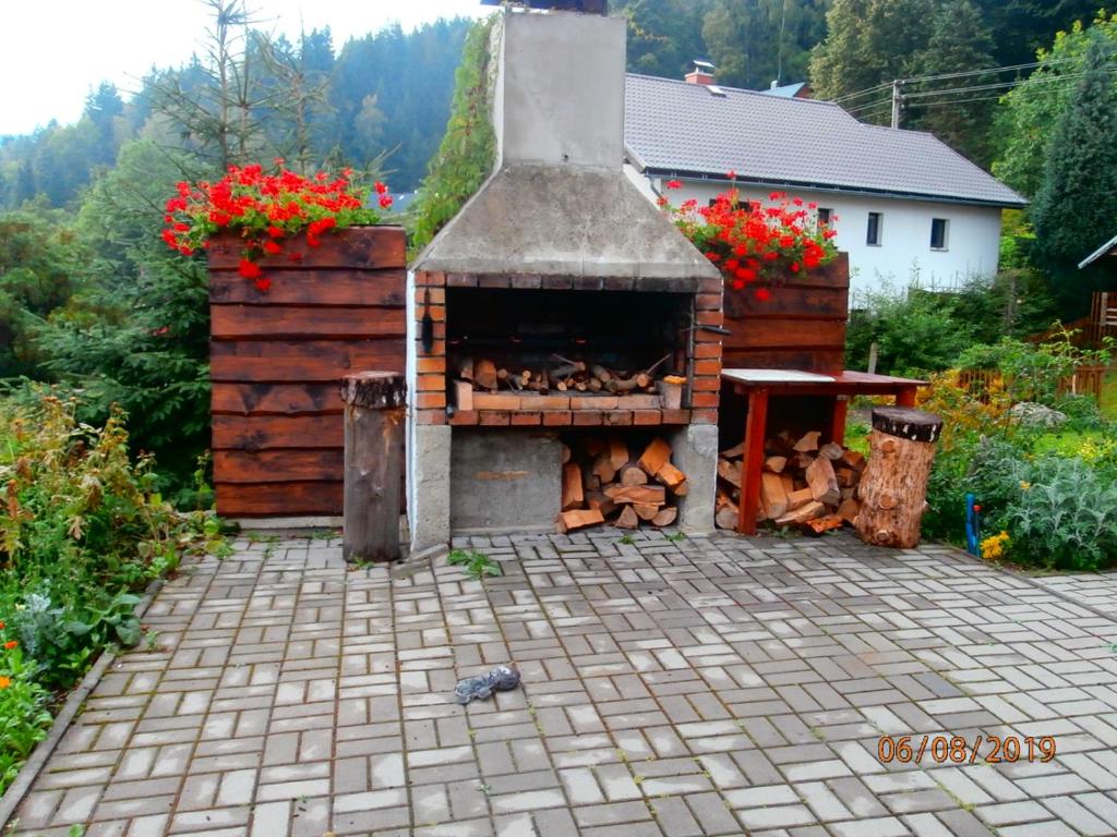 an outdoor pizza oven with flowers in a yard at Apartman Aya in Janov nad Nisou