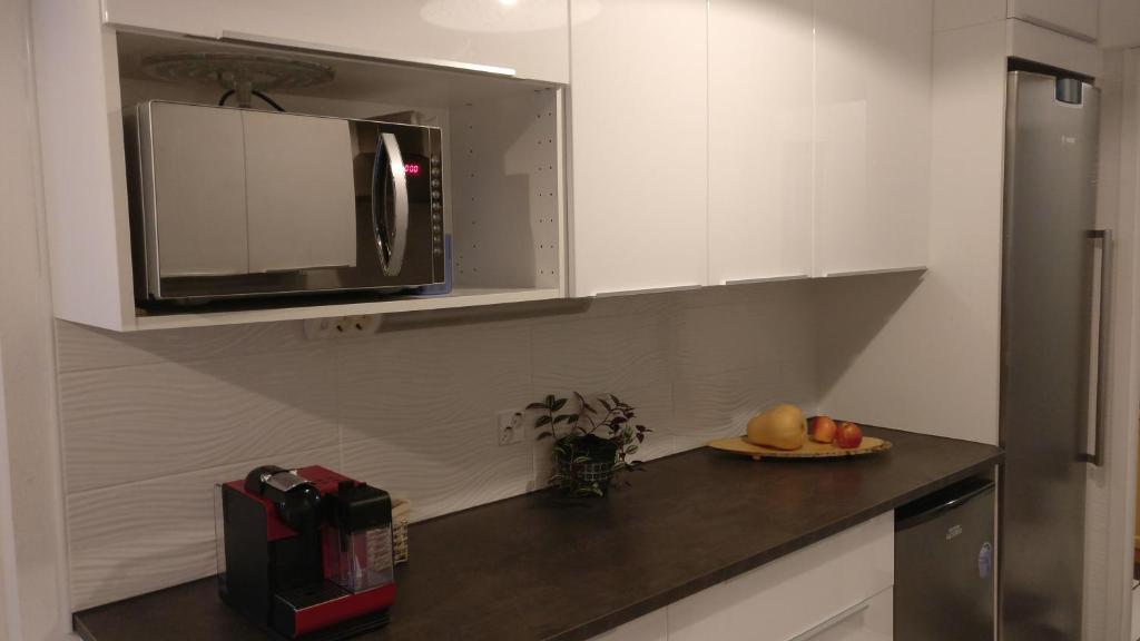 a kitchen with a microwave and a plate of fruit on a counter at 4 km to the Jyväskylä city center afoot, cute apartment with free parking in Jyväskylä