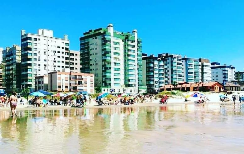 a beach with buildings and people in the water at Cobertura Beira Mar in Capão da Canoa