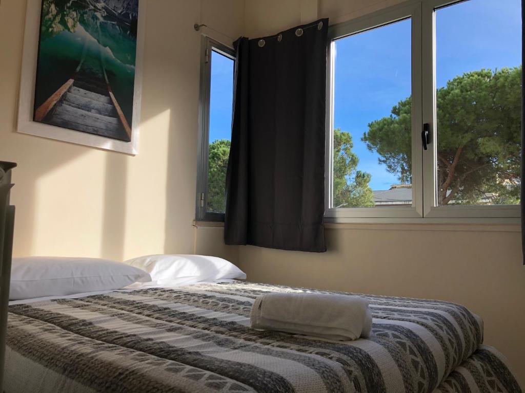 1 dormitorio con 2 camas y 2 ventanas en Beach Apartments in Montesilvano, en Montesilvano