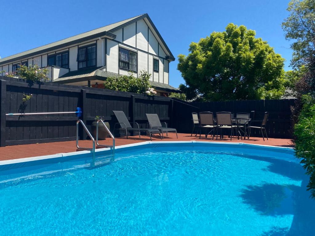 a swimming pool in front of a house at Knightsbridge Court Motor Lodge in Blenheim