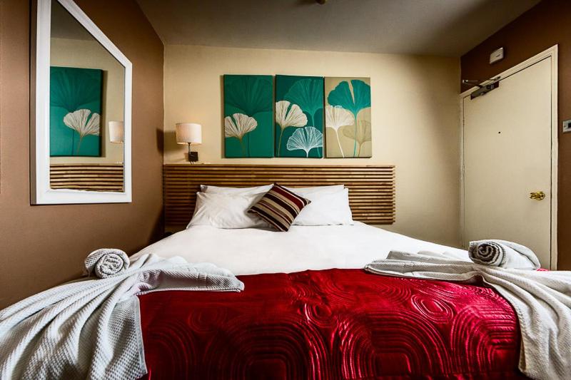 een slaapkamer met een groot bed en een rode deken bij Dockside Hotel in Londen