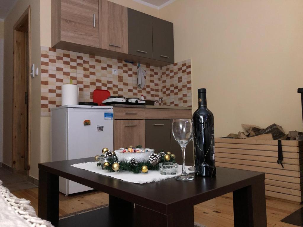 a kitchen with a table with a bottle and a wine glass at Apartmani Sredojevic in Kaludjerske Bare