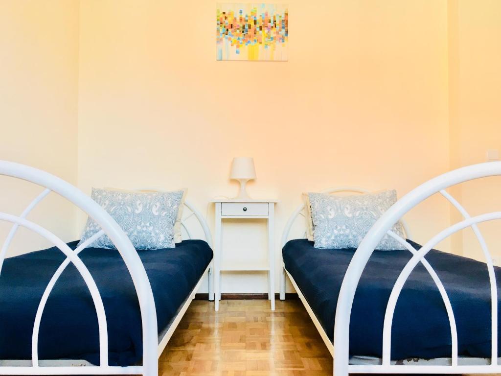 a bedroom with two beds and a table with a lamp at Casa dos Azulejos in Matosinhos