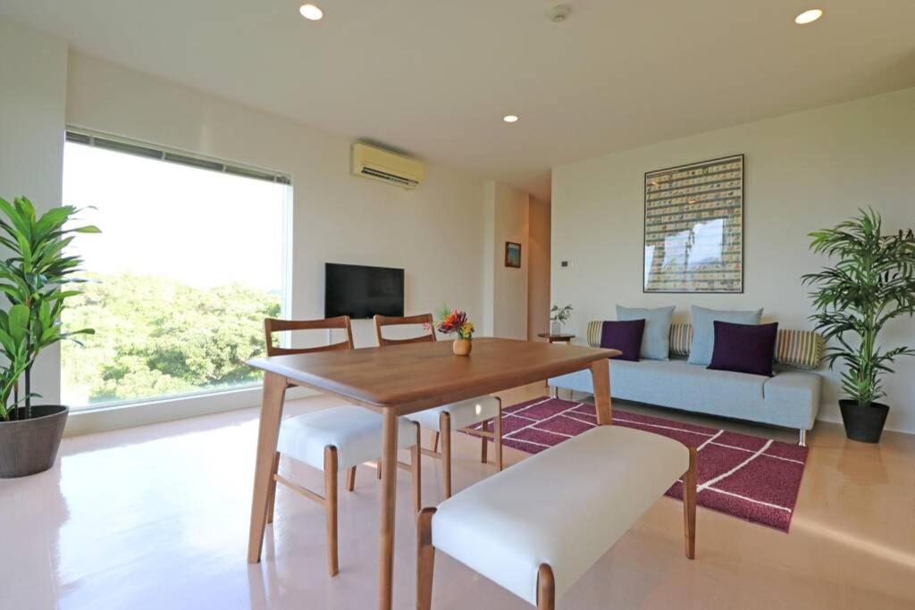 a living room with a table and chairs and a couch at 読谷村カービラハウス ow2 in Jima
