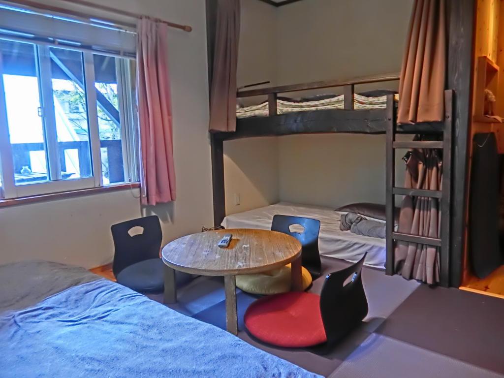 a room with two bunk beds and a table and chairs at Hakuba Kaze no Ko in Hakuba