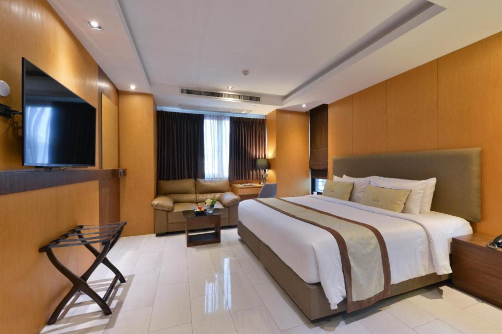 Habitación de hotel con cama grande y TV en Syama Suite Sukhumvit 20 en Bangkok