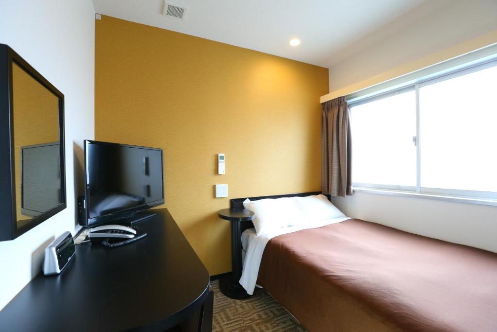 a hotel room with a bed and a tv at Urbain Tokyo Haneda Kamata in Tokyo