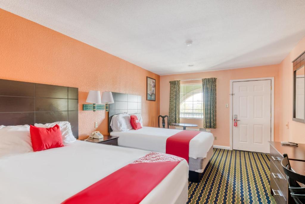 2 camas en una habitación de hotel con paredes de color naranja en OYO Hotel Channelview I-10, en Channelview