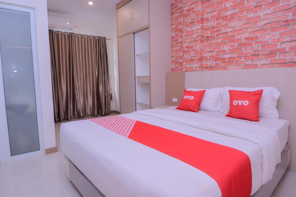 a bedroom with a large bed with two red pillows at SUPER OYO Capital O 2018 Ring Road Guest House Syariah in Banda Aceh