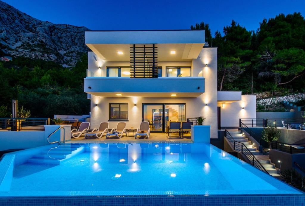 une villa avec une piscine en face d'une maison dans l'établissement Villa Leona a luxury villa near Makarska, heated pool, à Živogošće