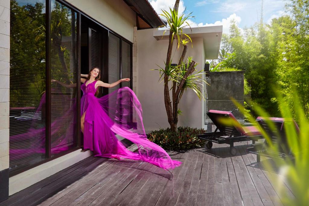 a woman in a pink dress standing on a porch at The Ayu Kintamani Villa at Toya Devasya in Kintamani