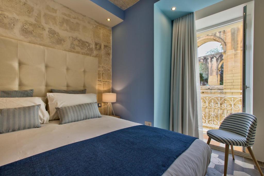 a bedroom with a bed and a large window at Barrakka Suites in Valletta
