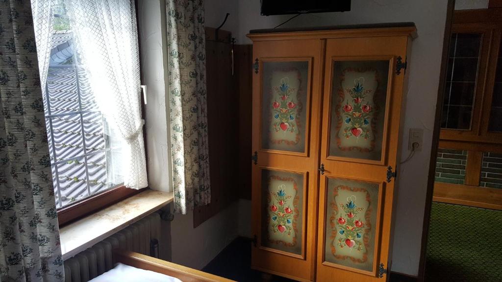 a wooden cabinet in a room next to a window at Pension Haus Seidenweber in Schmallenberg