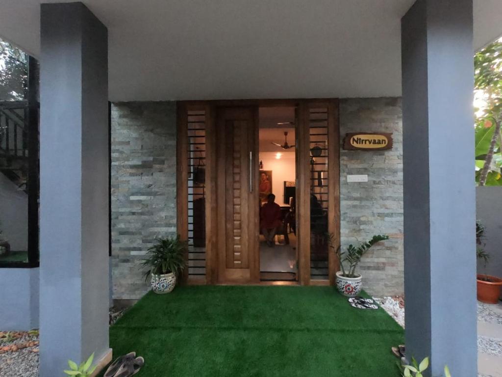 une porte d'entrée d'une maison avec une pelouse verte dans l'établissement Nirrvaan homestay, à Varkala