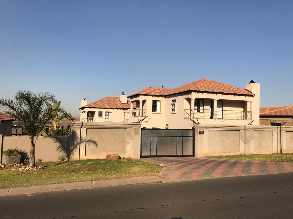 a large white house with a fence at Malu Guest House in Witbank