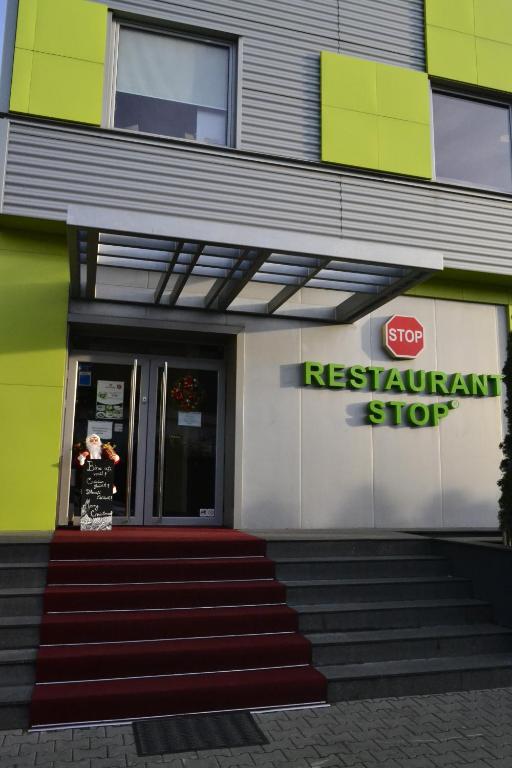a woman is standing outside of a restaurant sign at Stop Hotel in Braşov