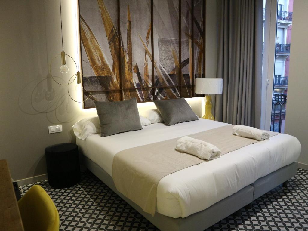 a bed with white sheets and pillows in a room at YOU & CO. Quart Boutique in Valencia