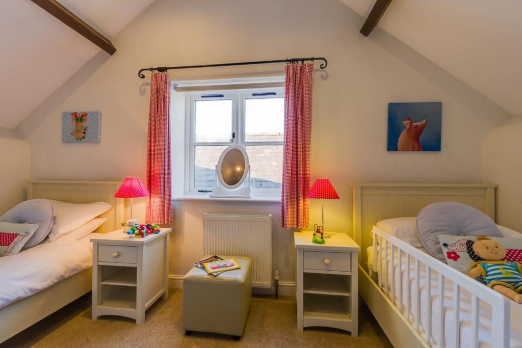 ein Schlafzimmer mit zwei Einzelbetten und einem Fenster in der Unterkunft Birchill Farm & Cottages - Bramble Cottage in Great Torrington