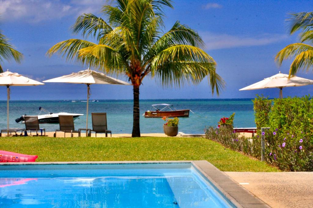 una piscina junto a una playa con sombrillas en L'Escale 3 bedrooms Sea View and Beachfront Suite by Dream Escapes, en Tamarin
