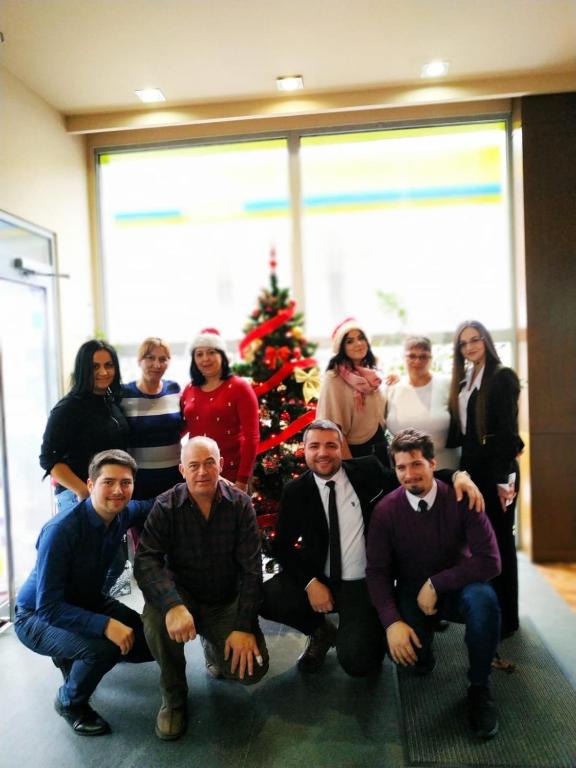 a group of people posing for a picture in front of a christmas tree at Stop Hotel in Braşov