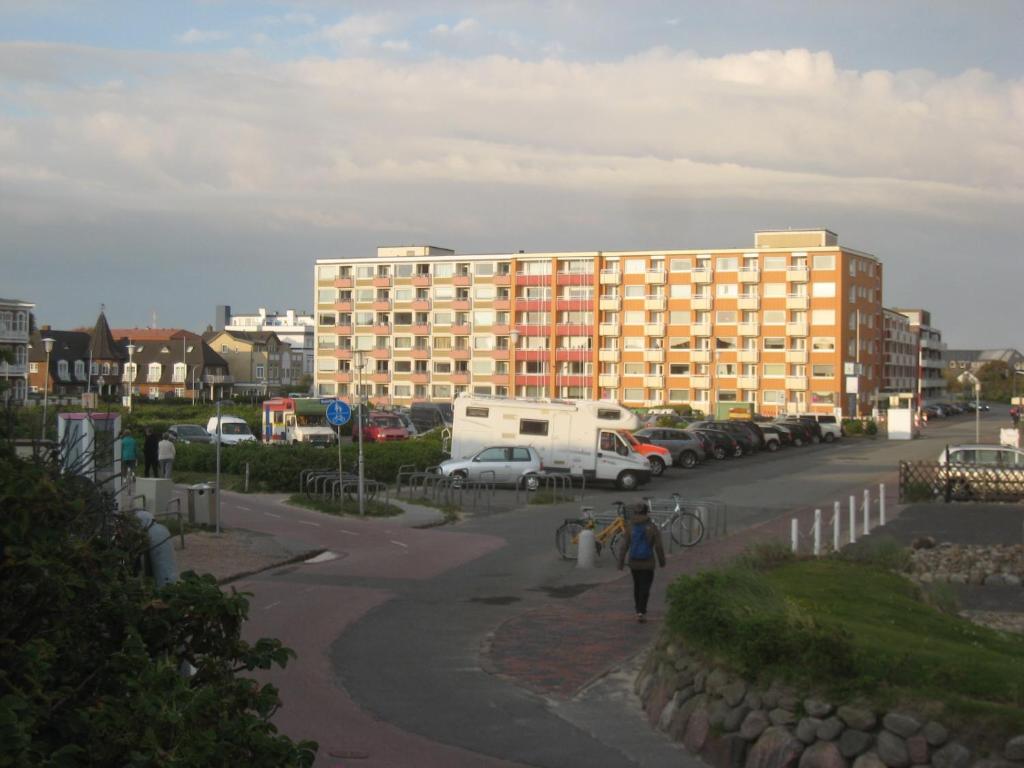 une personne marchant dans un parking avec un bâtiment dans l'établissement App. Hölscher 21, à Westerland