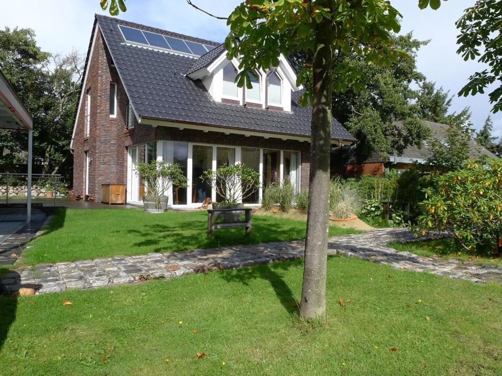 une maison avec un arbre dans la cour dans l'établissement App. Hookipa EG/UG, à Westerland