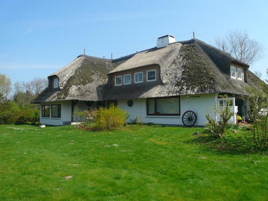 a house with a thatched roof on a green yard at Teewelkenhüs Schwalbennest in Archsum