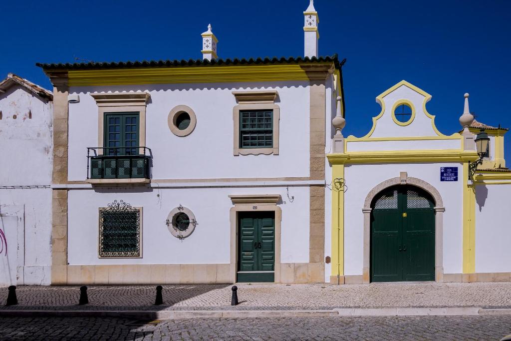 a building with two green doors and a church at Faro Tradicional House - City center in Faro