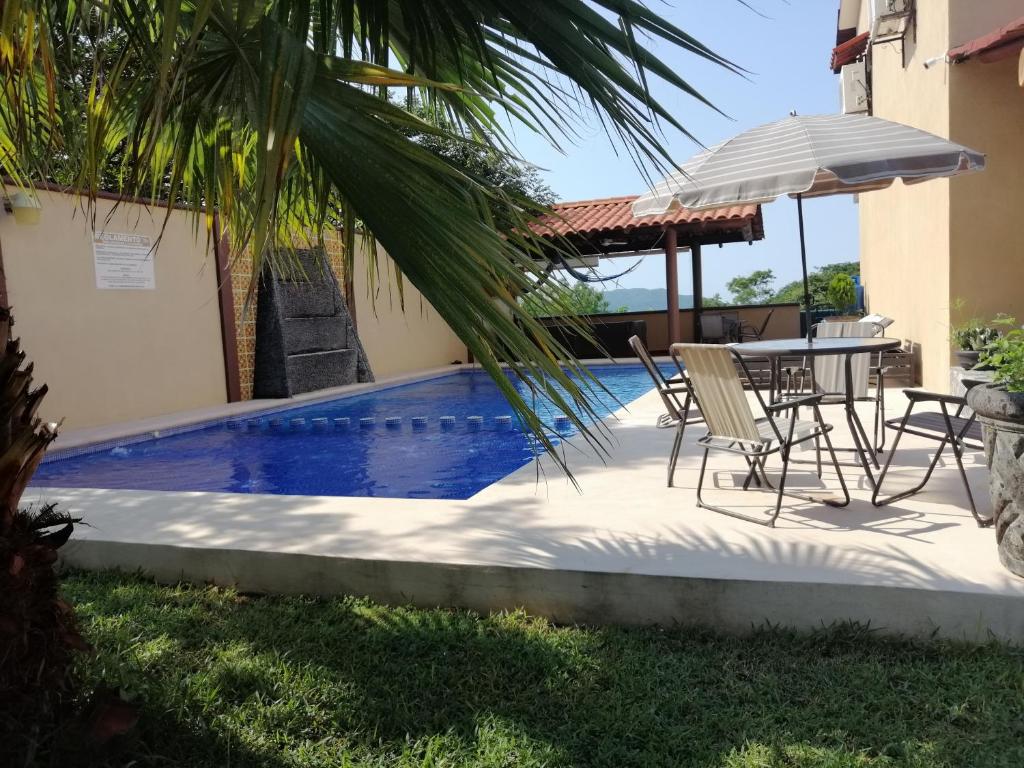 a patio with a table and chairs next to a pool at Villas victoria mirador in Zihuatanejo