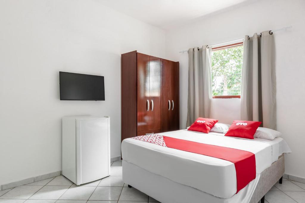 a bedroom with a large white bed with red pillows at OYO Pousada Tia Léo Campinas in Campinas