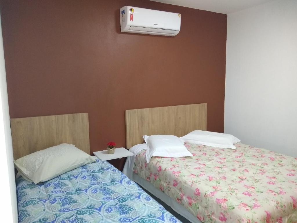 a bedroom with two beds and a air conditioner at Aluguel Por Temporada JCL6 in Gramado