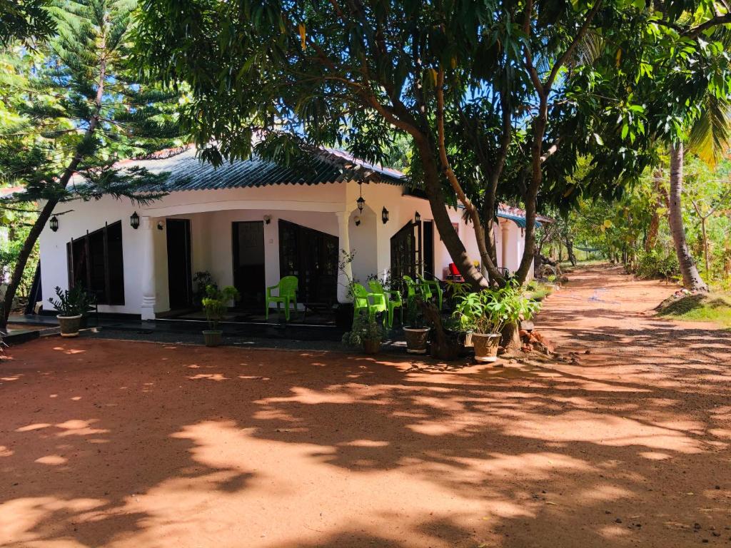 una casa blanca con árboles delante de ella en New Dambulla City Hostel en Dambulla
