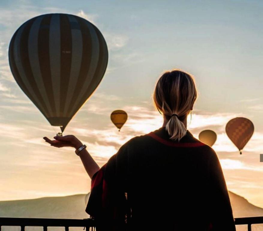 a woman is looking up at hot air balloons at Cappadocia Elite Stone House in Göreme