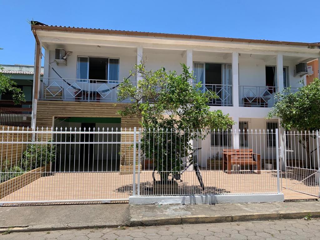 una casa blanca con una valla delante en Lagoa da Conceição Apartments, en Florianópolis