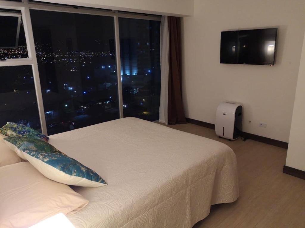 - une chambre avec un lit et une fenêtre donnant sur la ville dans l'établissement El mejor apartamento en excelente ubicación., à San José