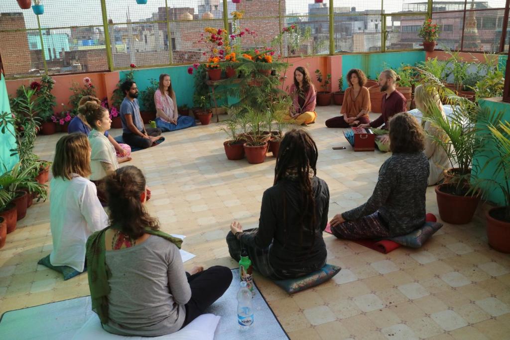 a group of people sitting in a room with plants at Tara Guest House in Varanasi