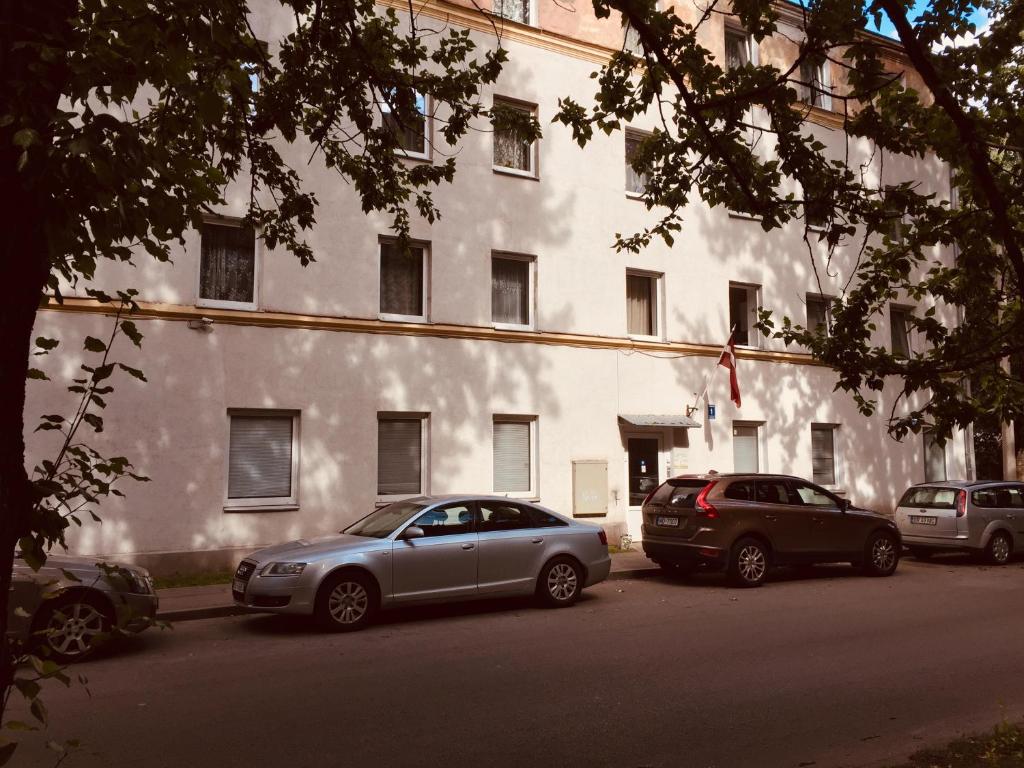 zwei Autos, die vor einem weißen Gebäude geparkt sind in der Unterkunft Sala Apartments in Riga