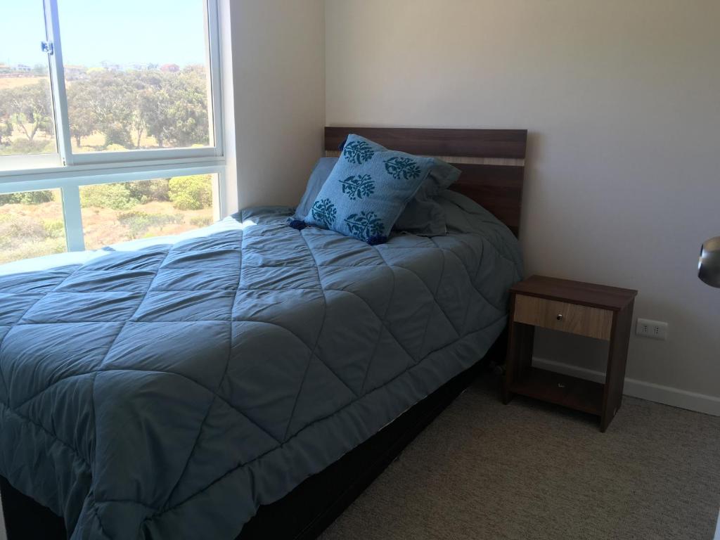 um quarto com uma cama com uma almofada azul e uma janela em Departamento en Los Molles em Los Molles