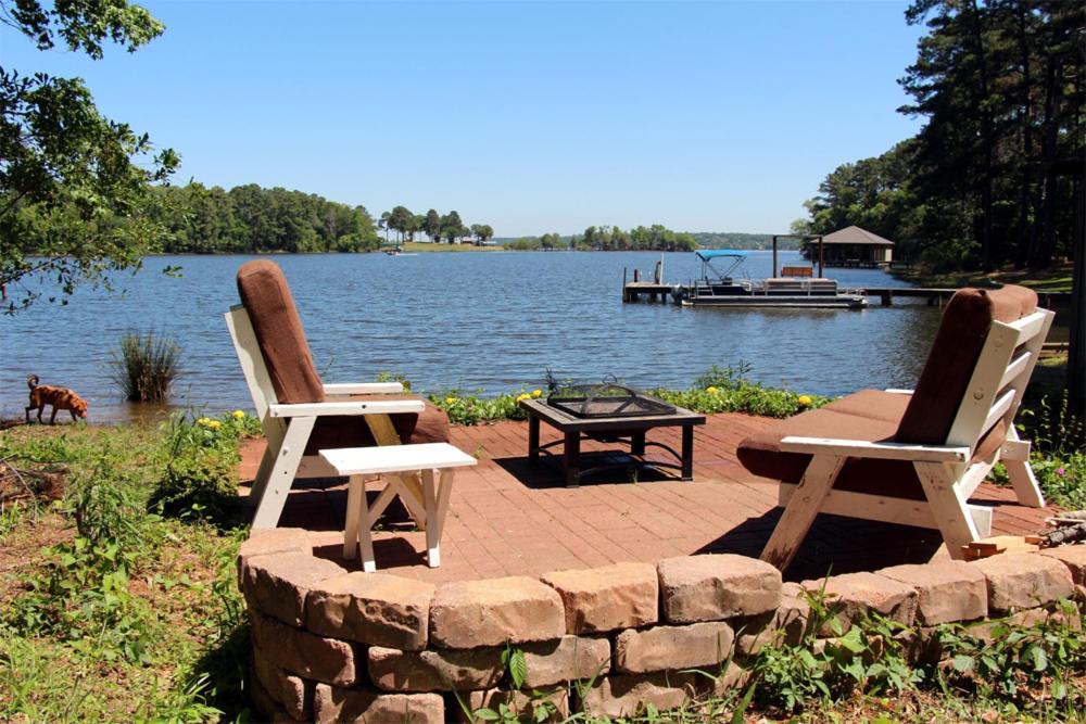 2 Stühle und ein Tisch auf einer Backsteinterrasse am Wasser in der Unterkunft Frankston Home with Deck and Fishing on Lake Palestine! in Coffee City