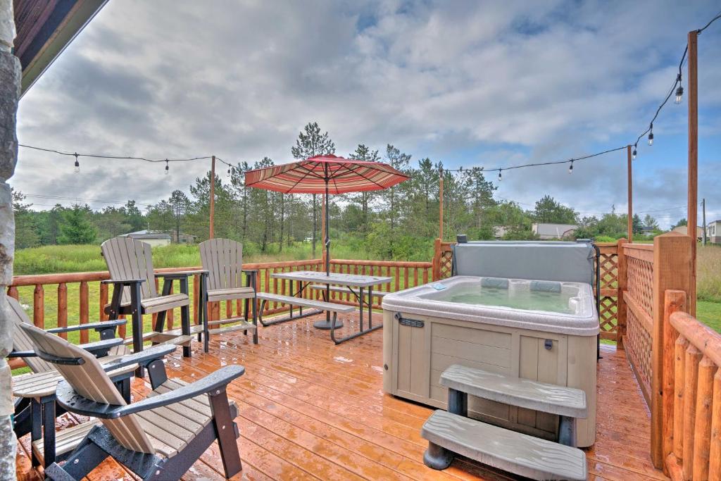 Benezette的住宿－Rustic Benezette Cabin with Porch, Hot Tub and Fire Pit，平台上设有带桌子和遮阳伞的天井。