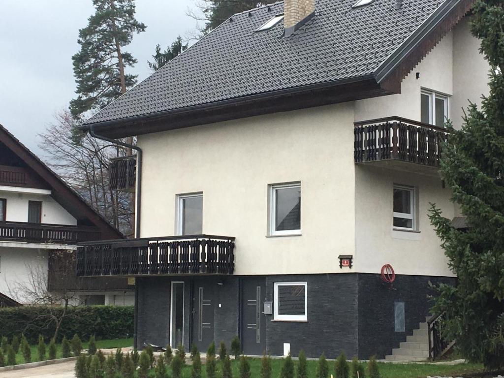 uma casa branca com um telhado preto e uma varanda em Kasita Bled Apartments em Bled