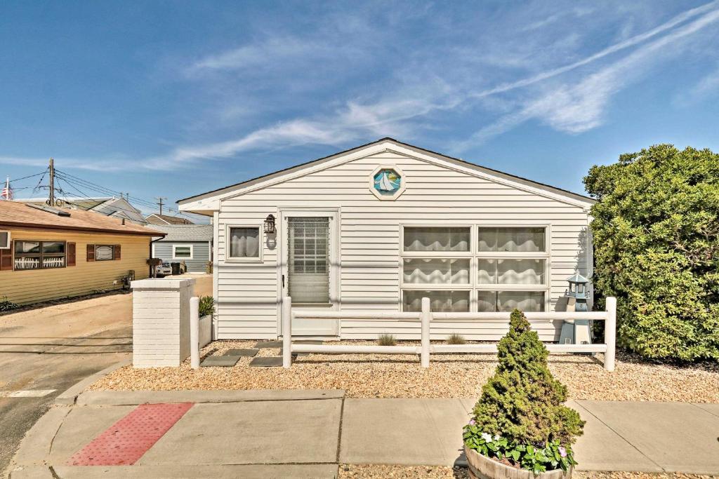 uma casa branca com uma cerca à frente. em Beachy Lavallette Cottage with Outdoor Shower, Patio em Lavallette