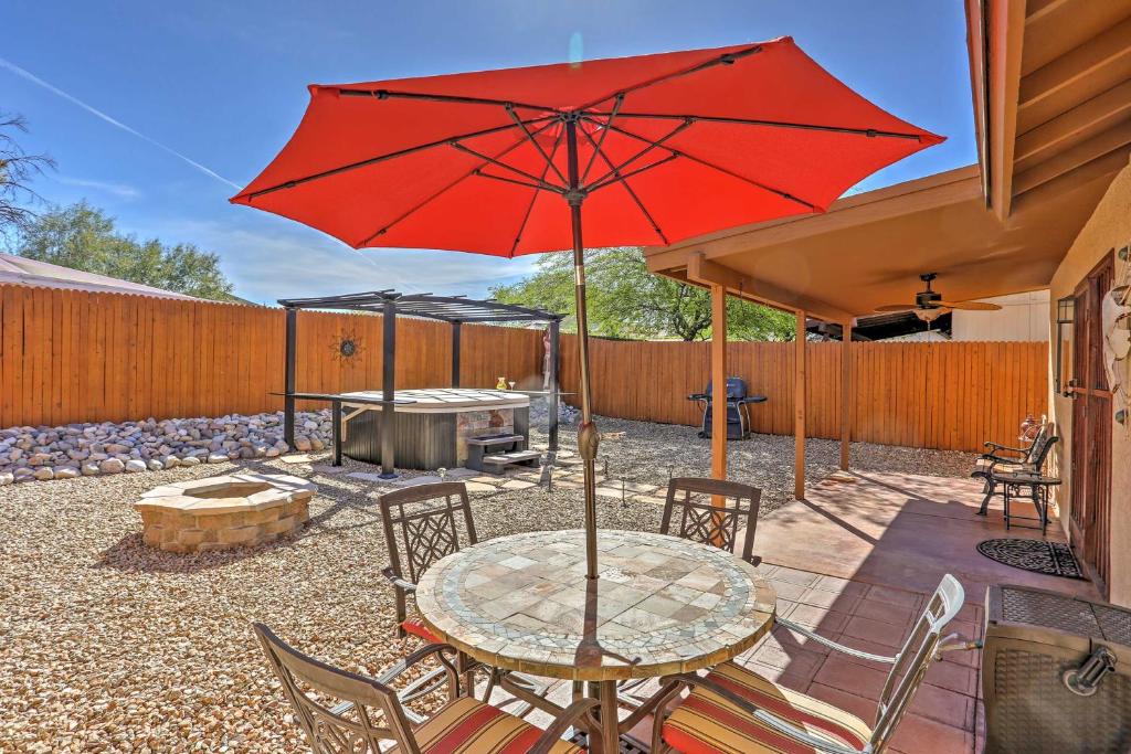 um pátio com uma mesa com um guarda-chuva vermelho em East Tucson House with Private Backyard and Fire Pit em Tucson