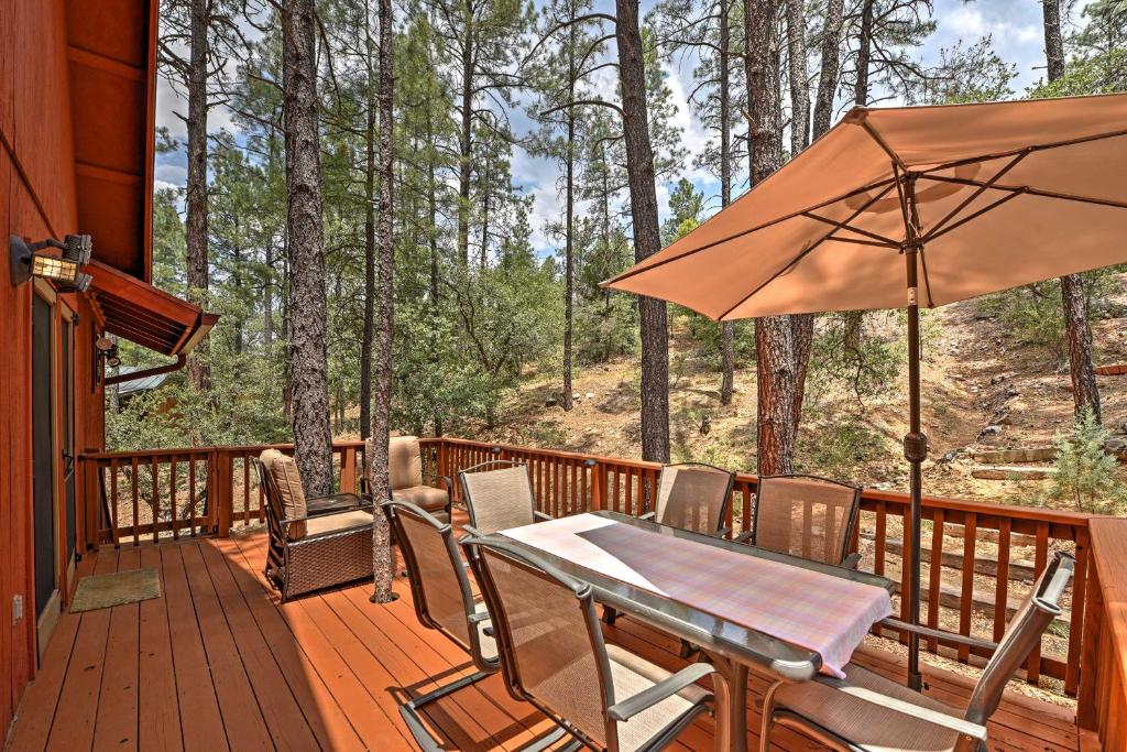 a wooden deck with a table and an umbrella at Prescott Cabin with Beautiful Forest Views and Deck! in Prescott