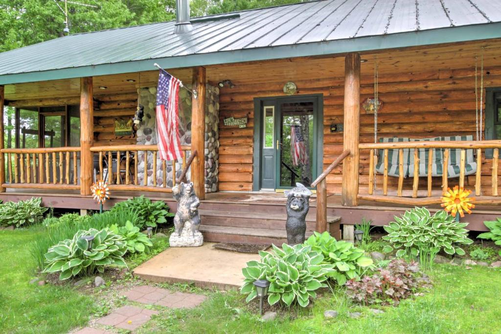 ein Blockhaus mit einer Veranda und einer amerikanischen Flagge in der Unterkunft Scenic Cabin on 2 Acres Near Lake Holcombe Marina! in Holcombe