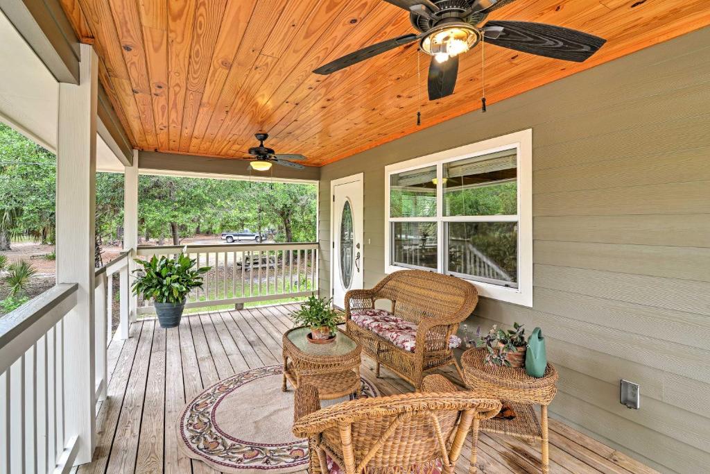 - une terrasse couverte avec des chaises en osier et un ventilateur de plafond dans l'établissement Crystal River Cottage on 1 Acre with Deck and Porch!, à Yankeetown