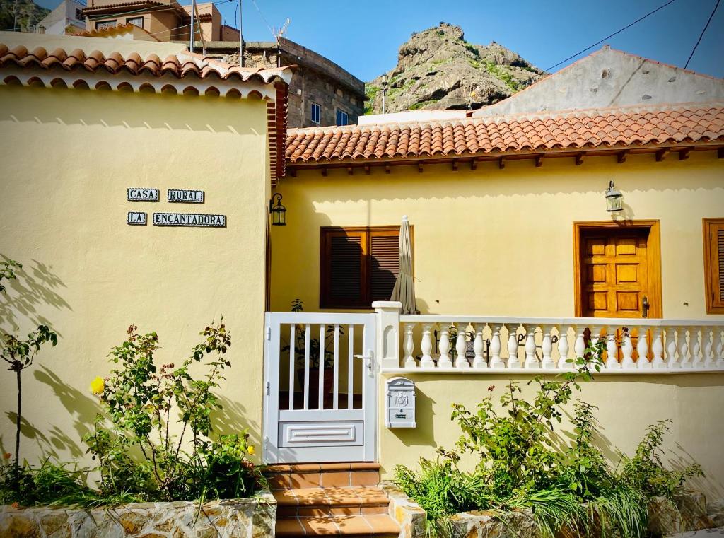 Casa amarilla con puerta blanca y balcón en Casa rural La Encantadora en Vallehermoso