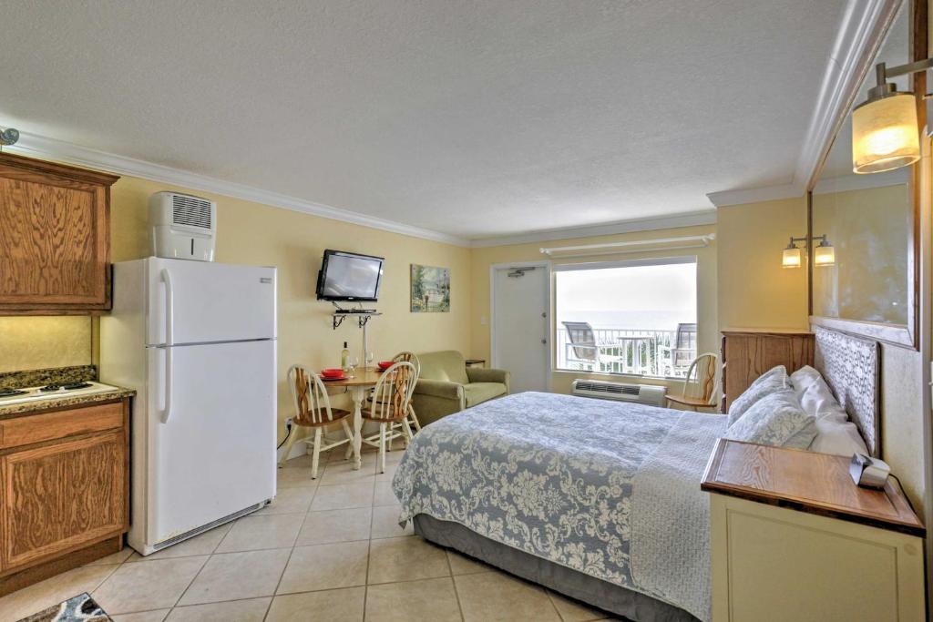 a bedroom with a bed and a kitchen with a refrigerator at Daytona Beach Studio with Oceanfront Balcony and Pool! in Daytona Beach